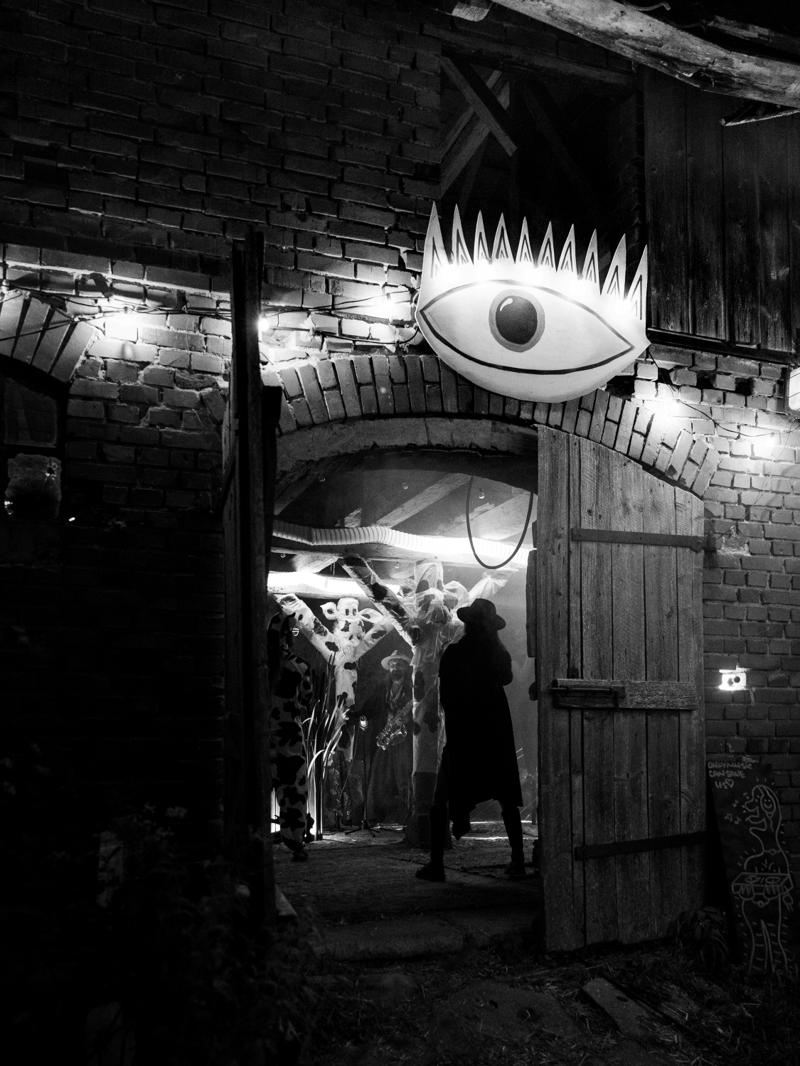 The entrance to an old brick barn lit at night, with a large painted eye above the door