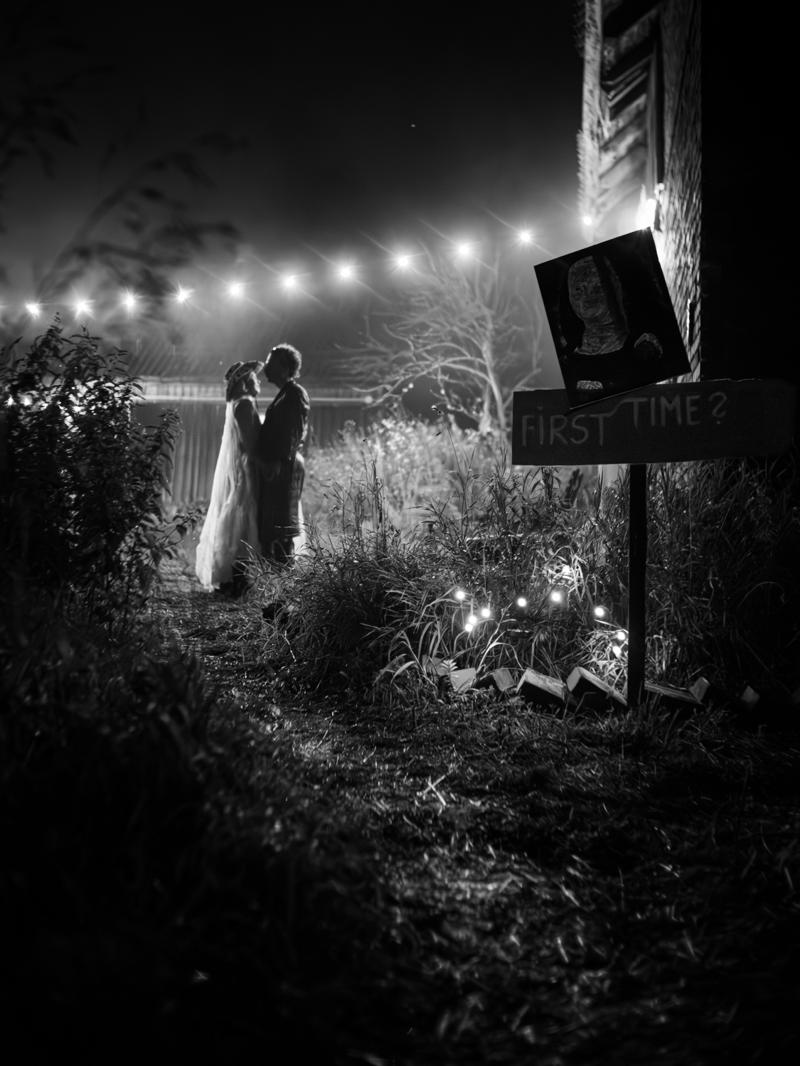 A couple embracing under string lights beside a hand-painted 